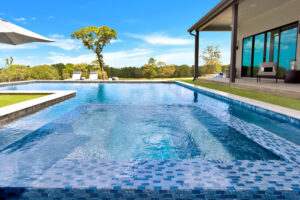 L-Shaped Pool with spa and blue glass tile