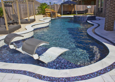 Freeform pool design with marble tile, tanning ledge and glass tile raised spa